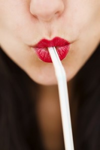 Closeup of a woman's lips drinking with straw.