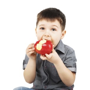 Close-up portrait of a little boy eating red apple
